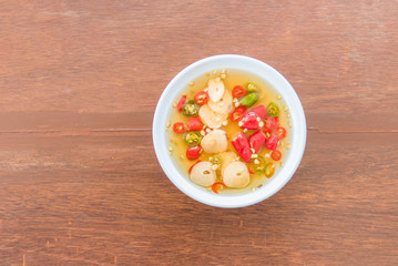 Fish sauce, chilli in a white cup on a wooden table
