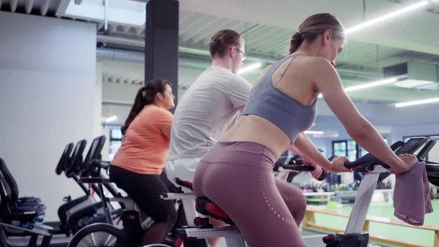 Man and women spinning on fitness bikes in the gym