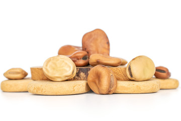 Lot of whole fresh brown bean vicia faba on tree stump isolated on white background