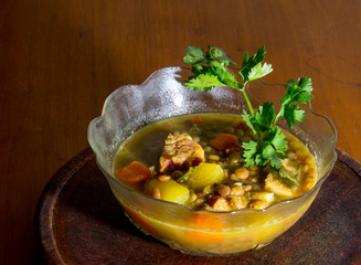 Small plate with lentil and vegetable soup garnished with a coriander branch