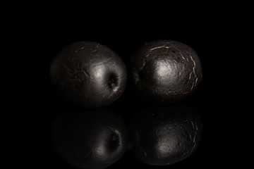 Group of two whole canned black olive isolated on black glass