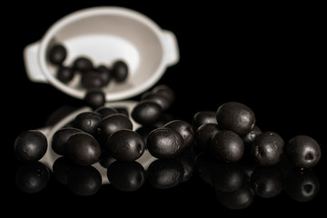 Lot of whole canned black olive in ceramic stewpan isolated on black glass