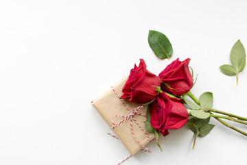 Composition of gift and bouquet of red roses on white background . Happy Valentines Day. Top view. Copyspace