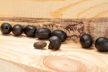 Lot of whole canned black olive on wooden stand with olive stone