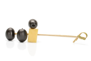 Group of three whole canned black olive with bamboo skewer and piece of cheese isolated on white background