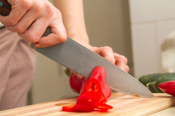 Chef slicing red paprika on a kitchen table