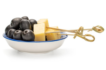 Lot of whole canned black olive on porcelain saucer with bamboo skewer and piece of cheese isolated on white background