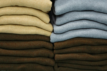 Warm clothing neatly folded on a store shelf. Clothes storage. Size range.