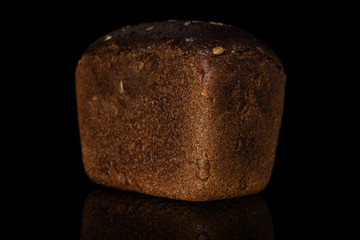 One whole fresh baked dark bread loaf isolated on black glass