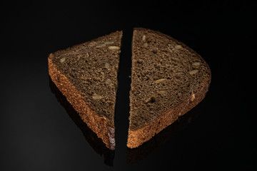 Group of two slices of fresh baked dark bread on black glass