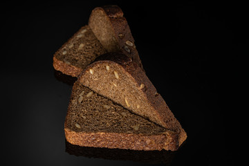 Group of six slices of fresh baked dark bread on black glass