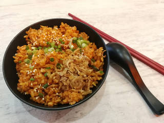 Kimchi Fried Rice in black bowl  on white wood background.Korean food style.