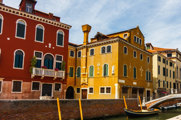 Grand Canal in Venice with boats and gandules docket motor boat near the bridge. Colorful residential house and small bridges cross the canal.