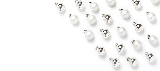 White and silver christmas balls pattern, minimal style. Christmas decorations on a white background, top view, flat lay.