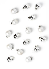 White and silver christmas balls pattern, minimal style. Christmas decorations on a white background, top view, flat lay.