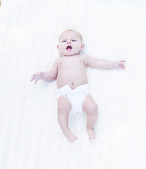 Portrait of cute baby boy lying in bed with open mouth. Above view of little toddler in diaper...