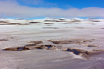 Panorama of Iceland emptiness with melting snow, mountains and cloudy skies. Landscape of Northern Iceland in springtime.