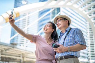 Senior couples who smile happily are taking selfies with a smartphone.