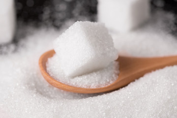 Sugar close-up. Sugar sand and sugar cubes poured from a wooden spoon.