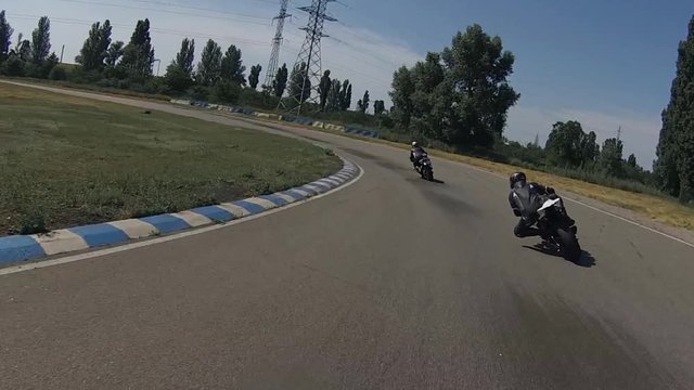 ZAPORIZHIA, UKRAINE - JUNE 17, 2019: black bike quickly overtakes the blue motorcyclist at the turn of the racetrack and accelerates forward.