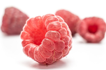 Group of four whole fresh crimson raspberry isolated on white background