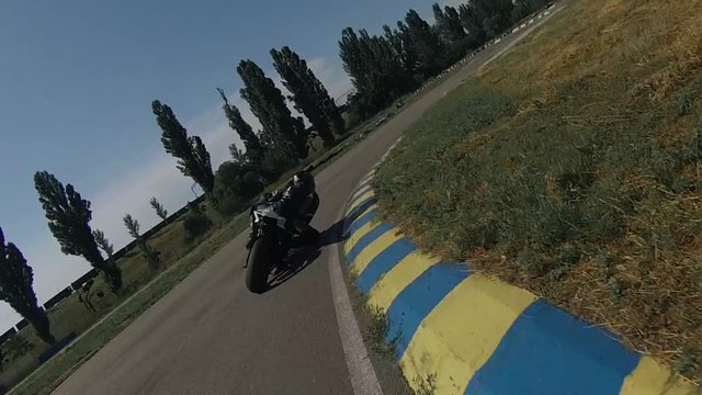 ZAPORIZHIA, UKRAINE - JUNE 17, 2019: black racer in leather motorcycle gear rides along a racetrack turning left and right.