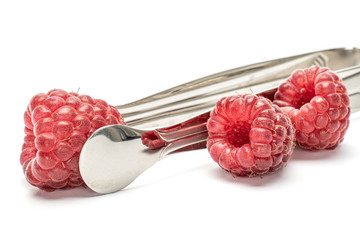 One whole fresh crimson raspberry with steel fork isolated on white background