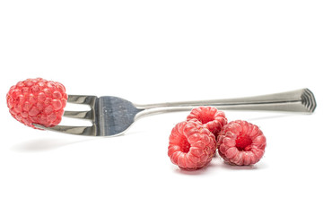 Group of four whole fresh crimson raspberry with steel fork isolated on white background