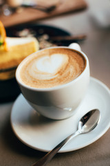 Single white ceramic cup of fresh brewed cappuccino on a saucer in cafe or restaurant.