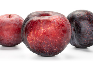 Group of three whole fresh red plum isolated on white background