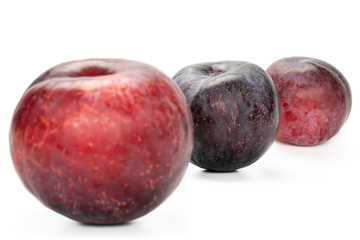 Obraz premium Group of three whole fresh red plum isolated on white background