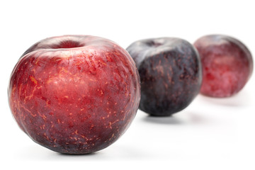 Group of three whole fresh red plum front focus isolated on white background