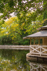 Landscape with detail of small house on the edge of a pond with autumnal vegetation, in vertical, in the El Capricho park in Madrid, Spain
