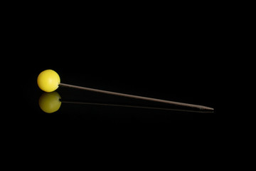 One whole haberdashery item yellow needle isolated on black glass