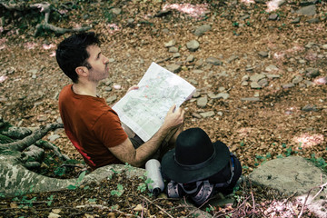 Hiker locating a path in the forest with a map