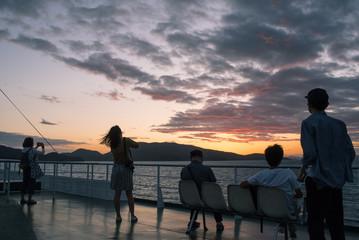 Obraz premium Passengers enjoying sunset from ferry to Takamatsu Port, Kagawa, Japan 香川県・高松港に向かうフェリーから夕日を見る乗客