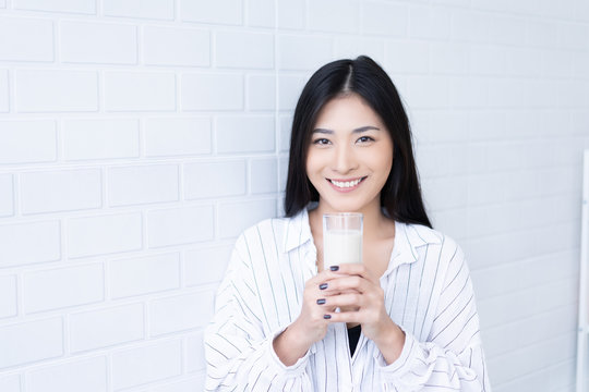 Happy Young Asian Woman Drinking Milk From The Glass After Exercise.over White Background, Shake Looking At Camera In The Living Room At Home