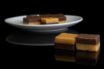 Group of eight whole sweet brown caramel chocolate candy on white ceramic plate isolated on black glass