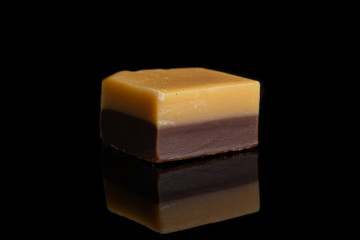 One whole sweet brown caramel chocolate candy isolated on black glass