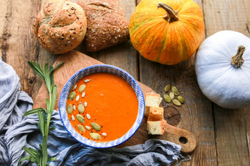 Vegetarian autumn pumpkin cream soup with seeds. Seasonal autumn food - pumpkin soup with thyme. Pumpkin soup with herbs, cream, breadcrumbs and parmesan, served in a bowl, top view. Place for text