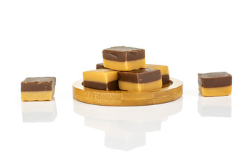 Group of seven whole sweet brown caramel chocolate candy on bamboo coaster isolated on white background