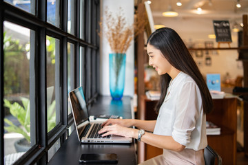 Asian young business women working with new project modern loft,laptop in coffee shop cafe, Analyze plans, papers, hands texting keyboard.Generic design notebook,technology or startup business concept