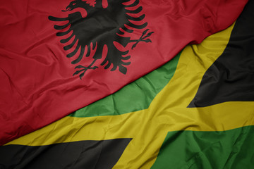 waving colorful flag of jamaica and national flag of albania.
