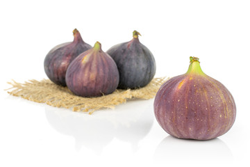 Group of four whole fresh purple fig on natural sackcloth isolated on white background