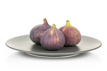 Group of three whole fresh purple fig on gray ceramic plate isolated on white background