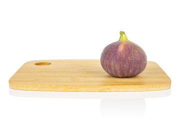 One whole fresh purple fig on bamboo cutting board isolated on white background