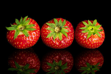 Group of three whole fresh red strawberry isolated on black glass