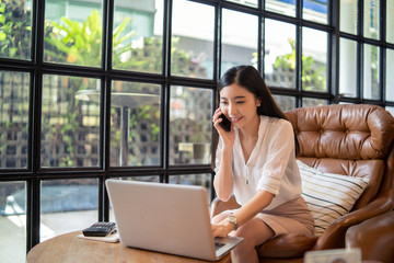 Smiling Business girl working in office with laptop,Happy Asian business woman using phone sitting...
