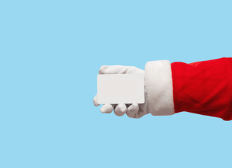 Santa Claus hand holding plastic credit card over isolated blue background.