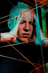 a teenager at a party got tangled up among the ropes. young man in depression in the light of the neon on black background